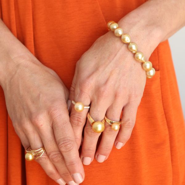 woman modelling gold pearl rings