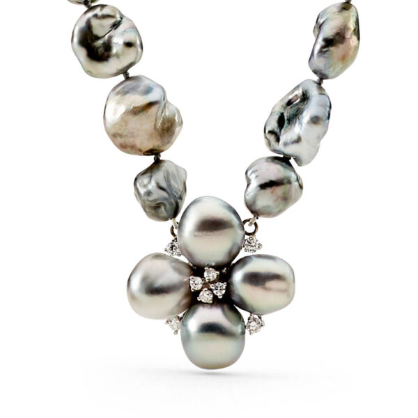 A strand of Tahitian Keshi Pearls containing 36 Keshis, mid grey in colour, with a AAA luster, grade 1 and 10 to 12mm in size. At the center of the strand is a floral setting, with 4 silver Tahitian Keshi pearls, with 8 diamonds totaling 0.35 carats. The necklace is strung to 49 cm in length and fastens with a baroque shaped 18 carat white gold clasp